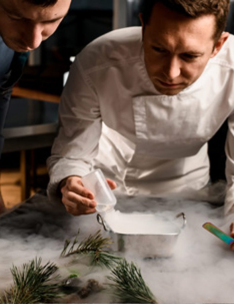 Due chef lavorano insieme in una cucina, mentre preparano piatti pronti gourmet con ingredienti freschi