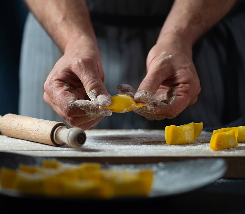 Uno chef di Sistema Gusto prepara della pasta fresca su un tagliere.
