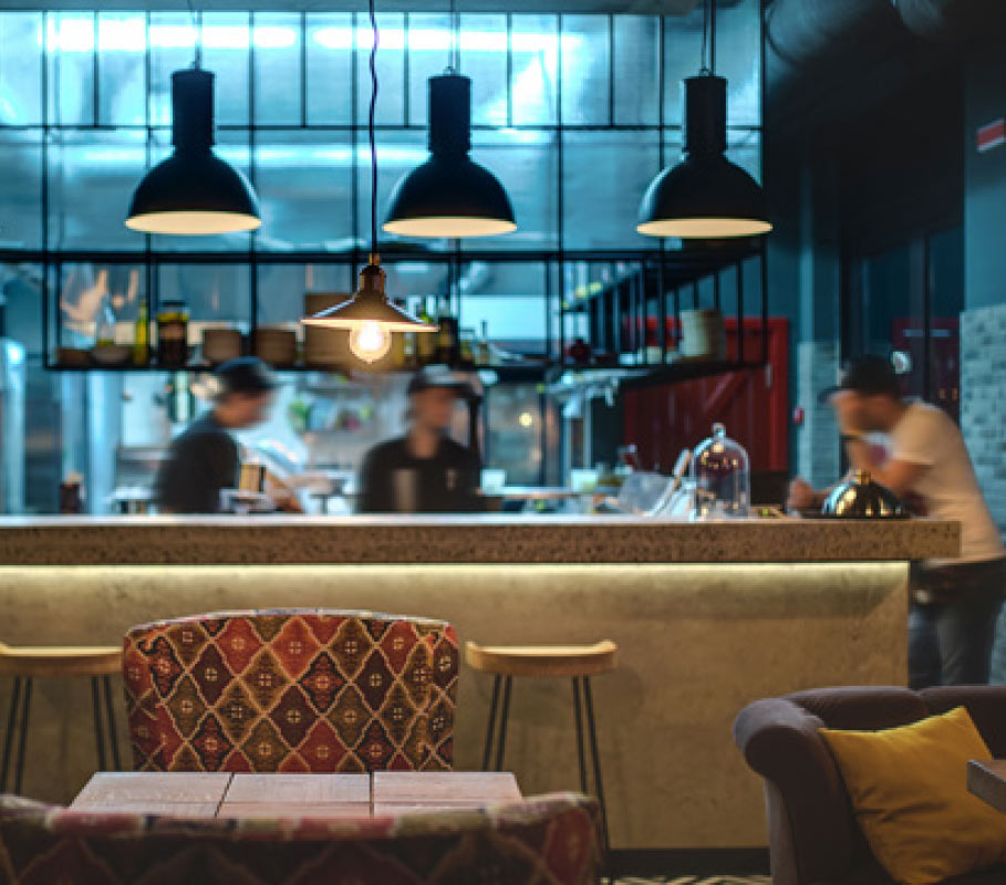 Un bar affollato con persone sedute al bancone, mentre conversano e gustano bevande in un'atmosfera vivace.